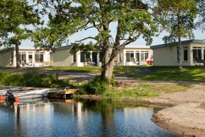 a boat on a river in front of a building at Ringsjöstrand Camping, Hotell och Stugby in Hörby