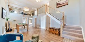 a living room with a staircase and a table at Brock's Beach House in Saint Gennys