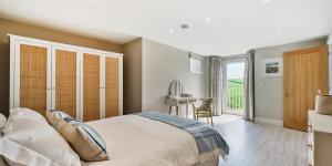 a bedroom with a bed and a desk and a window at Brock's Beach House in Saint Gennys