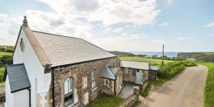 an old stone church with a road next to it at Brock's Beach House in Saint Gennys