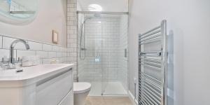a white bathroom with a toilet and a shower at Brock's Beach House in Saint Gennys +33 photos
