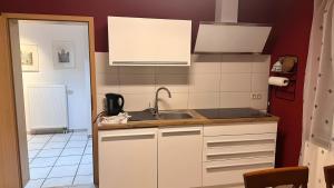 a kitchen with white cabinets and a sink at Ruhige Fewo Hinzweiler in Hinzweiler +10 photos