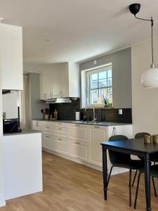 a kitchen with white cabinets and a table in it at Lilla Hotellet Blidö in Blidö