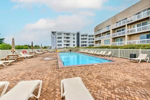 a swimming pool with lounge chairs and a building at Steps to Brigantine Beach: New Jersey Beach Condo in Brigantine