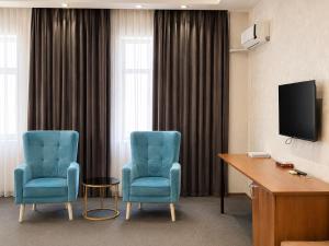 a room with two blue chairs and a desk and a television at Arena Hotel Tartar in Terter