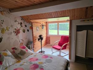 a bedroom with a bed and a red chair at Chambres à l'Orée du bois in Souancé-au-Perche
