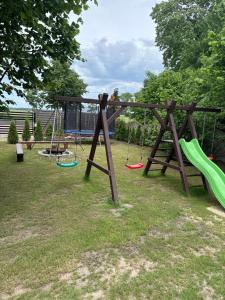a playground with three swings in a yard at Domek z basenem in Kodrąb