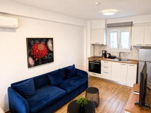 a living room with a blue couch and a kitchen at Pool Access Danai 15,1 in Ofrínion