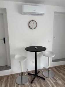 a table with three stools and a clock on a wall at Studio U Martina in Mariánské Lázně +2 photos
