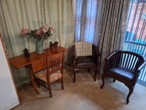 a desk with a vase of flowers and two chairs at De Windmolen in Centurion