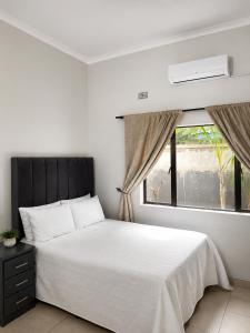 a bedroom with a white bed and a window at Wilo Residence in Victoria Falls