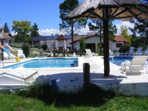 a swimming pool with an umbrella and chairs at COMPLEJO LLATANI in Los Reartes