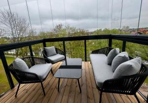 a balcony with three chairs and a couch on a deck at River View Apartment in the Park in Marijampolė