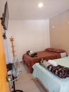 a room with two beds and a fan at Samay77 Ica in Ica