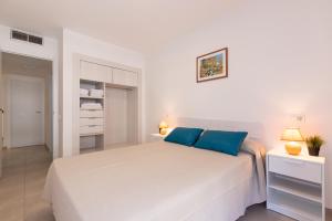 a white bedroom with a large white bed with blue pillows at Rentalmar Sol de España - Mas d'en Gran in Cambrils +28 photos