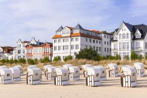 a row of white chairs in front of buildings at Strandhotel Bansiner Hof in Bansin