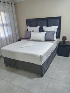 a bedroom with a large bed with white and purple pillows at Sydney's Guest House in Johannesburg