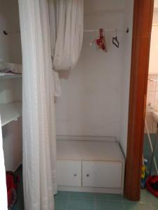 a small closet with a white curtain and a shelf at Almond Apartments Ground Floor Apt in Ofrínion