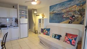 a living room with a couch and a painting on the wall at La Rose des Sables - face à la mer in Frontignan +22 photos