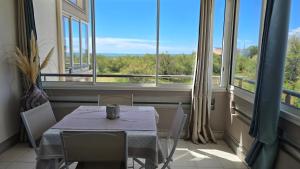 a table and chairs in a room with large windows at La Rose des Sables - face à la mer in Frontignan