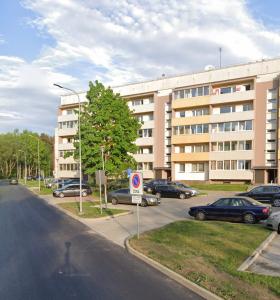a parking lot with cars parked in front of a building at Harmony Apartments Lux in Liepāja
