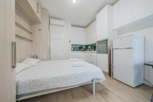 a white bedroom with a bed and a refrigerator at Cristel Apartment - 15 min da Milano in Cormano