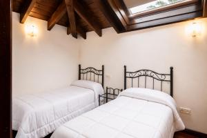 two beds in a bedroom with a skylight at Tejasturias |Piscina, Pádel y Playa de La Franca in Noriega