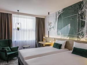 a hotel room with two beds and a chair at ibis Styles Kraków East in Krakow +46 photos