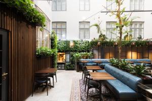 a restaurant with benches and tables and plants at Hotel Skt. Annæ in Copenhagen
