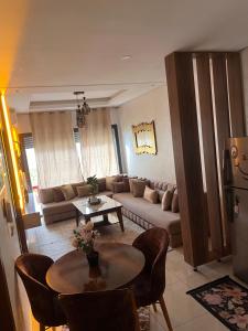 a living room with a couch and a table at Studio Luxe Bouznika Beach Piscine, Clim, Wi-Fi ,Check in 24h Plage 5 min in Bouznika