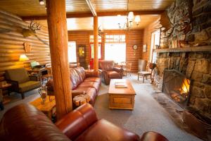 a living room with leather couches and a stone fireplace at Paradise Lodge and Bungalows in Lake Louise
