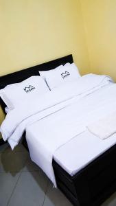 two beds in a room with white sheets and pillows at La casa Motel in Kahama