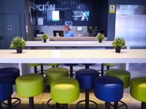 a bar with green and blue stools in a restaurant at ibis budget Bilbao City in Bilbao