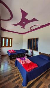 two beds in a room with a painting on the ceiling at Chaukhamba Pine Cottage & HomeStay in Rānsi