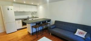 a living room with a blue couch and a kitchen at Appartement Villars Colmars in Villars-Colmars