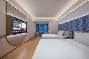 a hotel room with two beds and a flat screen tv at Manxin Hotel Xian Bell Tower in Xi'an