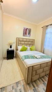 a bedroom with a large bed with green pillows at Serenity Elgon Stay in Eldoret +1 photo