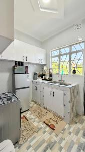 a kitchen with white cabinets and a large window at Serenity Elgon Stay in Eldoret