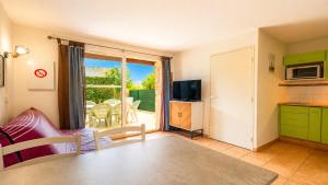 a living room with a table and a kitchen with a balcony at Samaria Village N08 - 2P4 in Agde