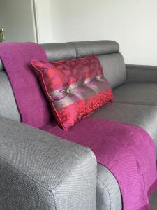 uma almofada sentada num sofá com um tapete roxo em Appartement Copenhague Disneyland em Montévrain