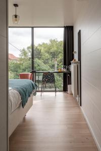 a bedroom with a bed and a desk and a window at B&B Armalot by Julia in De Panne