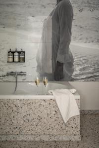 a man standing in a bath tub with two glasses of wine at B&B Armalot by Julia in De Panne +82 photos