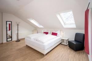 a bedroom with a white bed and a black chair at Hotel Garni Ammergauer Hof in Oberammergau