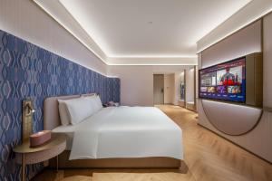 a hotel room with a large bed and a flat screen tv at Manxin Hotel Xian Bell Tower in Xi'an