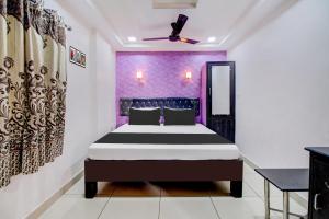 a bedroom with a bed and a purple wall at Hotel O Rajadhani in Guntūr