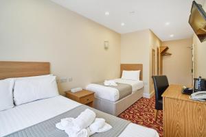 a hotel room with two beds and a television at Best Western London Ilford Hotel in Ilford +43 photos