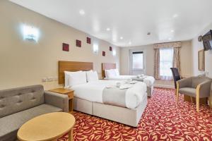 a hotel room with a large bed and a couch at Best Western London Ilford Hotel in Ilford
