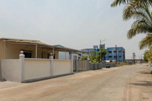 an empty road in front of a building with a palm tree at Ananda Villa in Igatpuri