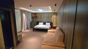 a bedroom with a bed and a couch and a chair at Polo Signature Hotel in Kaduna