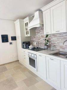 a kitchen with white cabinets and a sink at Relax House Sardara in Sardara
